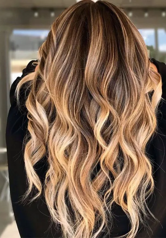 Melena rubia con mechas californianas peinada con ondas